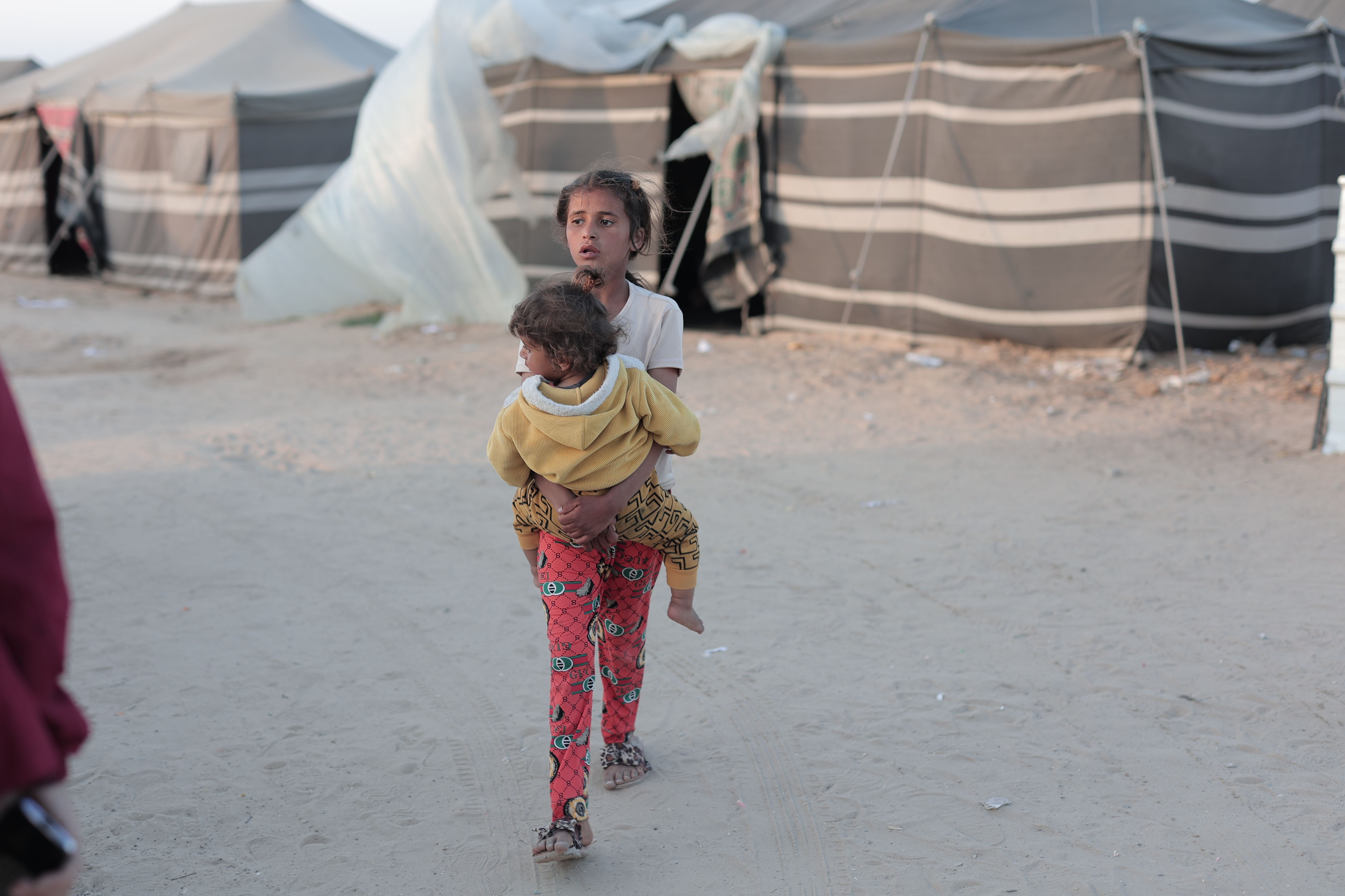 Girl carrying baby in refugee camp