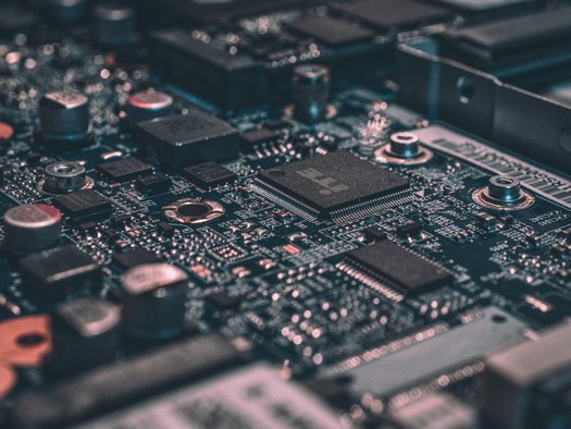 Close-up of a circuit board with a central microchip — representing products with digital elements that fall under the Cyber Resilience Act.